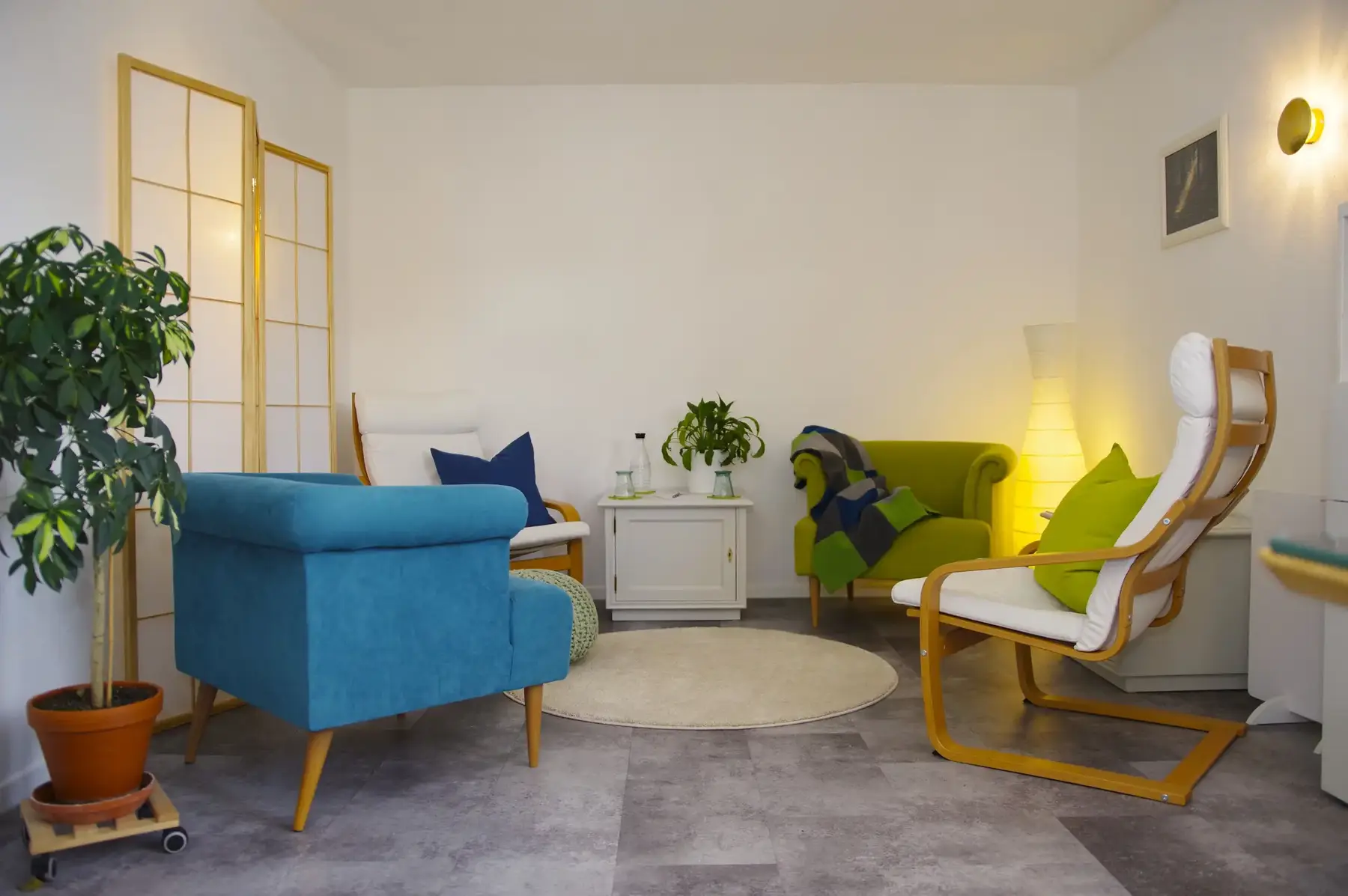Praxisraum mit blauem Sessel, Pflanze und Stehlampe